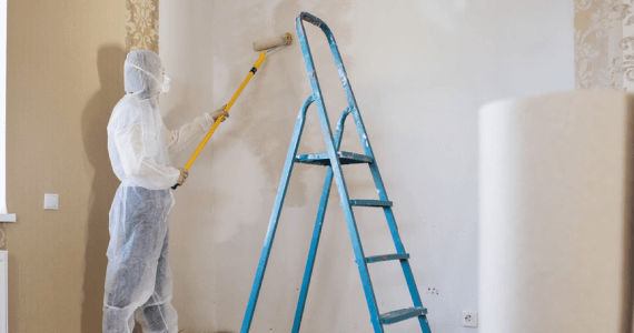 Imagen de un hombre pintando al lado de una escalera