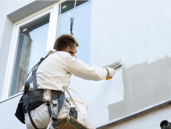 Imagen de un pintor pintando una fachada por fuera